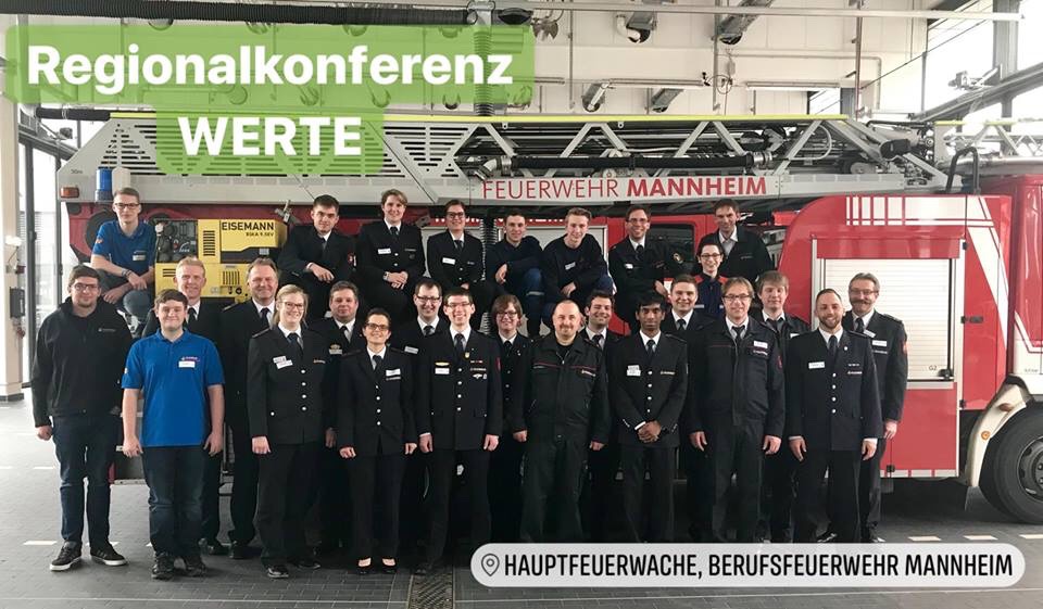 feuerwehrleute in Uniform vor einer Drehleiter in der Hauptfeuerwache Mannheim